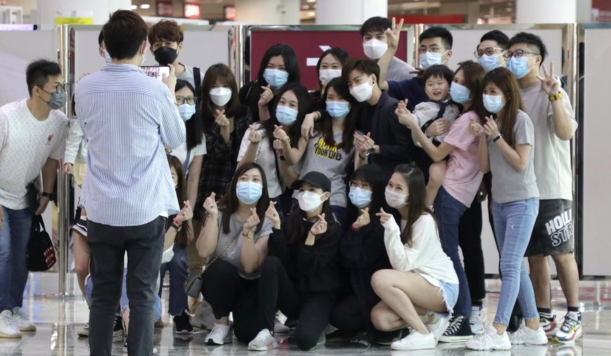 Malaysians and Singaporeans stranded in Macao during pandemic, pose for a photo before getting on a special AirAsia flight to Kuala Lumpur, in Macao airport, Thursday, April 8, 2021. About 50 people of various nationalities boarded a chartered flight from Macao to Malaysia on Thursday after many were stranded for months by the pandemic and border restrictions. (AP Photo)
