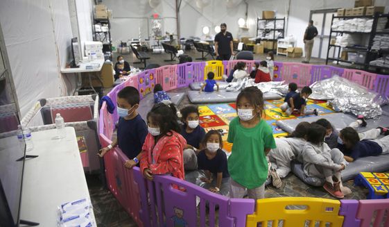In this March 30, 2021, file photo, young unaccompanied migrants, from ages 3 to 9, watch television inside a playpen at the U.S. Customs and Border Protection facility, the main detention center for unaccompanied children in the Rio Grande Valley, in Donna, Texas. Migrant families will be held at hotels in the Phoenix area in response to a growing number of people crossing the U.S.-Mexico border, authorities said Friday, April 9, 2021, another step in the Biden administration&#39;s rush to set up temporary space for them (AP Photo/Dario Lopez-Mills, Pool, File)