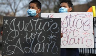 Jacob Perea, 7, left and Juan Perea, 9 holds signs on Tuesday, April 6, 2021, as they attend a press conference following the death of 13-year-old Adam Toledo, who was shot by a Chicago Police officer at about 2 a.m. on March 29 in an alley west of the 2300 block of South Sawyer Avenue near Farragut Career Academy High School. (AP Photo/Shafkat Anowar)