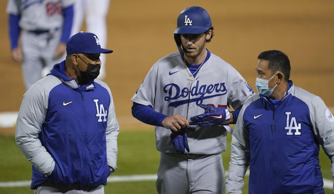 Los Angeles Dodgers&#x27; Cody Bellinger, center, walks off the field as he leaves the game with manager Dave Roberts, left, and a trainer during the ninth inning of a baseball game against the Oakland Athletics in Oakland, Calif., Monday, April 5, 2021. (AP Photo/Jeff Chiu)