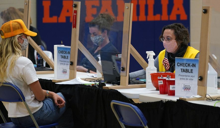 FILE - In this Tuesday, Nov. 3, 2020 file photo, an election judge checks in a voter at the La Familia Recreation Center in the Baker neighborhood south of downtown Denver. On Friday, April 9, 2021, The Associated Press reported on stories circulating online incorrectly asserting Major League Baseball had moved the All-Star game to Colorado because Georgia now requires an ID to vote, and yet Colorado also requires voter ID. But Colorado does not require an identification card to vote. Furthermore, Georgia already had a voter photo ID requirement, new sweeping rules include ID requirements to apply for a mailed ballot. (AP Photo/David Zalubowski)