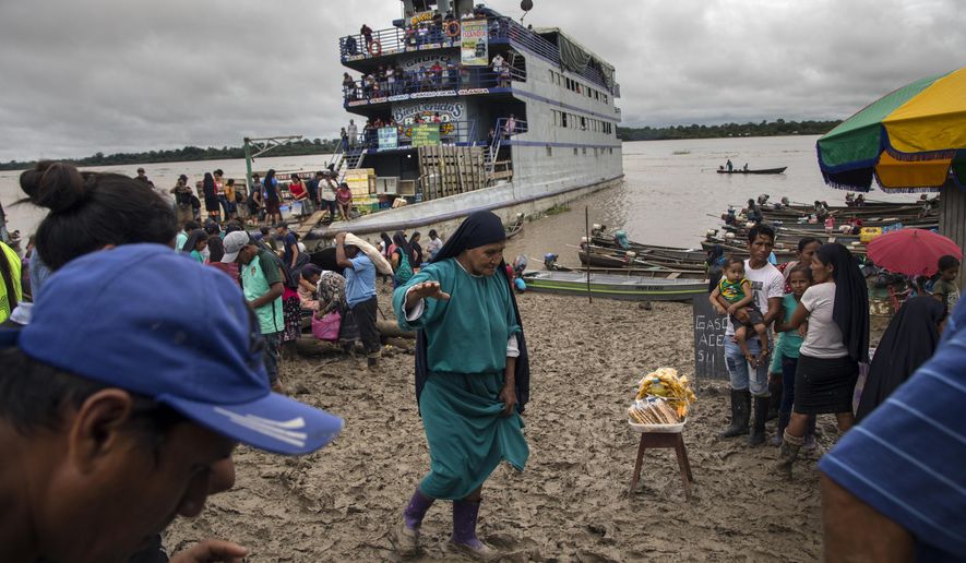 A member of the Israelites of the New Universal Pact religious group, holds out her right arm to maintain her balance as she walks through a market on the muddy banks of the Amazon River, in Alto Monte de Israel, Peru, Sunday, March 28, 2021. The political arm of the messianic group, the Agricultural People's Front of Peru, known as Frepap, has emerged as a potential favorite in Sunday's April 11th legislative elections. (AP Photo/Rodrigo Abd)