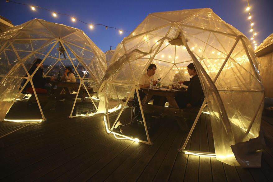 People enjoy outdoor dining at plastic bubbles, observing social distancing against the spread of the coronavirus at a restaurant near the Han River in Seoul, South Korea, Friday, April 9, 2021. (AP Photo/Ahn Young-joon) **FILE**