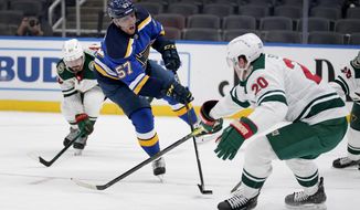 St. Louis Blues&#39; David Perron (57) shoots as Minnesota Wild&#39;s Marcus Johansson (90) and Ryan Suter (20) defend during the second period of an NHL hockey game Friday, April 9, 2021, in St. Louis. (AP Photo/Jeff Roberson)