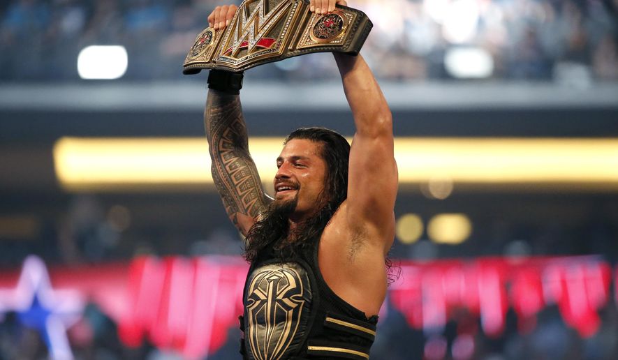 FILE - In this April 3, 2016, file photo, Roman Reigns holds up the championship belt after defeating Triple H during WrestleMania 32 at AT&amp;amp;T Stadium in Arlington, Texas.  WWE is set to welcome back fans for the first time in more than a year when 25,000 fans are expected on both Saturday, April 10, 2021 and Sunday nights for WrestleMania at Raymond James Stadium in Tampa, Fla.   (Jae S. Lee/The Dallas Morning News via AP, File)