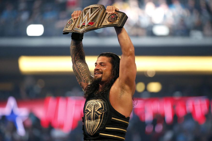 FILE - In this April 3, 2016, file photo, Roman Reigns holds up the championship belt after defeating Triple H during WrestleMania 32 at AT&amp;amp;T Stadium in Arlington, Texas.  WWE is set to welcome back fans for the first time in more than a year when 25,000 fans are expected on both Saturday, April 10, 2021 and Sunday nights for WrestleMania at Raymond James Stadium in Tampa, Fla.   (Jae S. Lee/The Dallas Morning News via AP, File)