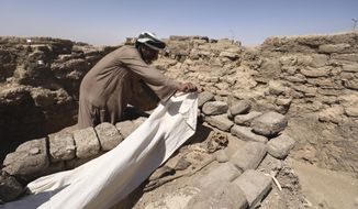 A man cover a skeleton in a 3,000-year-old lost city in Luxor province, Egypt, Saturday, April 10, 2021. The newly unearthed city is located between the temple of King Rameses III and the colossi of Amenhotep III on the west bank of the Nile in Luxor. The city continued to be used by Amenhotep III&#39;s grandson Tutankhamun, and then his successor King Ay. (AP Photo/Mohamed Elshahed)