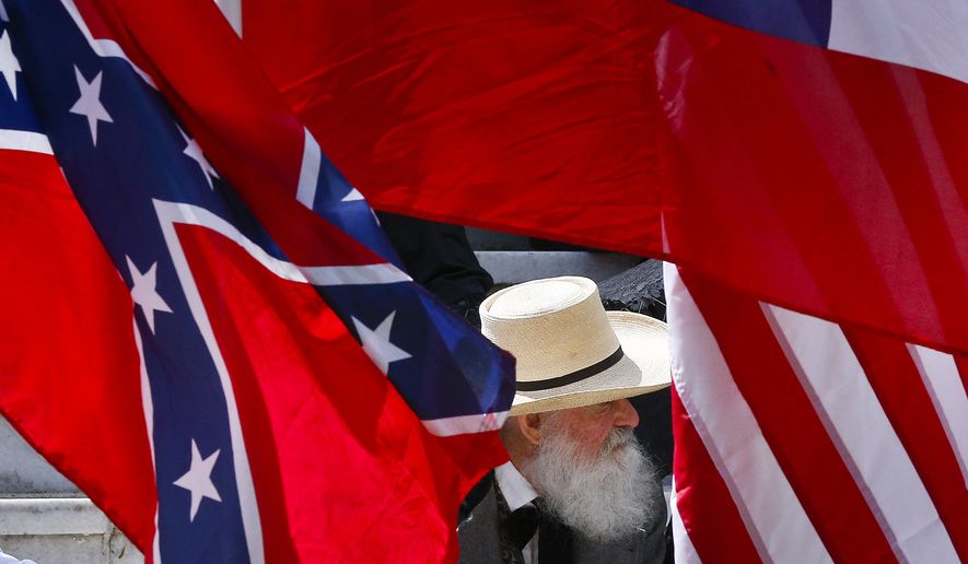 A man sits behind a Confederate flag during a celebration at the Alabama State Capitol to celebrate Confederate Memorial Day in Montgomery, Ala. (AP Photo/Brynn Anderson)