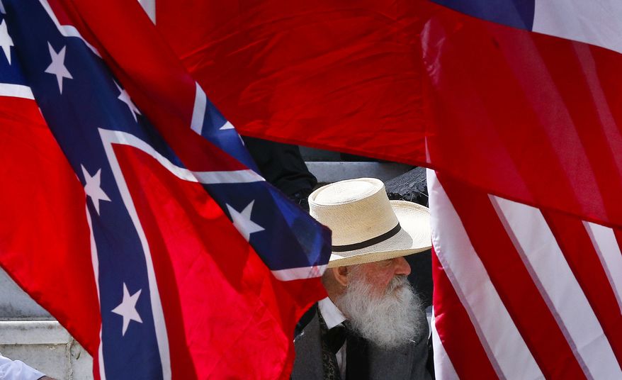 A man sits behind a Confederate flag during a celebration at the Alabama State Capitol to celebrate Confederate Memorial Day in Montgomery, Ala. (AP Photo/Brynn Anderson)