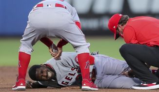 Los Angeles Angels manager Joe Maddon, top, leans over to check on Dexter Fowler who was injured during a play at second base against the Toronto Blue Jays during the second inning of a baseball game Friday, April 9, 2021, in Dunedin, Fla. (AP Photo/Mike Carlson)