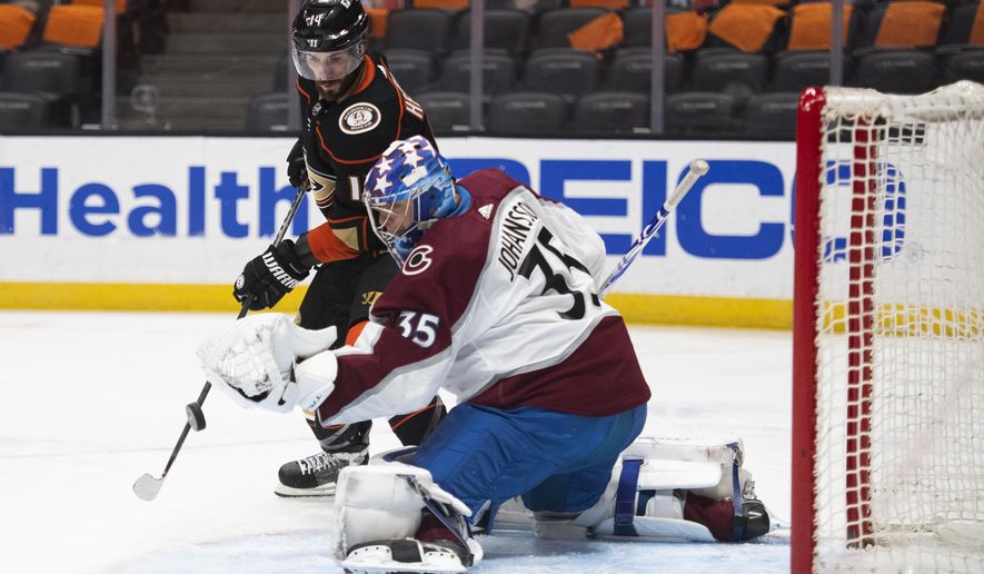 Anaheim Ducks center Adam Henrique, top, tries to deflect the puck in front of Colorado Avalanche goaltender Jonas Johansson in the second period of an NHL hockey game in Anaheim, Calif., Sunday, April 11, 2021. (AP Photo/Kyusung Gong)
