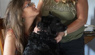 Angela Crowe, left, poses for a photo with her mother, Joan Antonuccio, right, while holding their dog  at their home in Tampa, Fla., on Tuesday, March 30, 2021.  A jury awarded $60 million to Crowe and Antonuccio in 2015 in a judgment against a former North Naples bar that served Crowe and her then-boyfriend too much alcohol on the night of the crash in 2003. Crowe and Antonuccio haven’t received a cent of that money. (Alex Driehaus/Naples Daily News via AP)