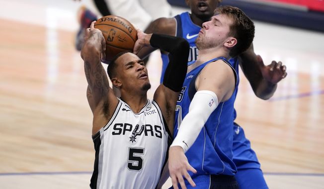 San Antonio Spurs guard Dejounte Murray, left, drives against Dallas Mavericks guard Luka Doncic, right, for a shot attempt in the first half of an NBA basketball game in Dallas, Sunday, April 11, 2021. (AP Photo/Tony Gutierrez)