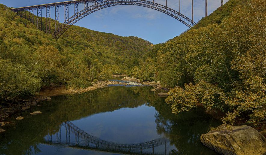 FILE - In this Oct. 9, 2019 file photo, the New River Gorge Bridge is seen from Fayette Station in Fayetteville, W.Va. A program launched Monday, April 12, 2021, will try to lure outdoor enthusiasts to live and work in West Virginia with enticements of $12,000 cash and free passes for a year for recreation destinations such as whitewater rafting and golf.. (F. Brian Ferguson/Charleston Gazette-Mail via AP, File)