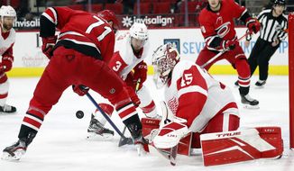 Carolina Hurricanes&#x27; Jesper Fast (71) tries to gather in the puck in front of Detroit Red Wings goaltender Jonathan Bernier (45) and Alex Biega (3) during the second period of an NHL hockey game in Raleigh, N.C., Monday, April 12, 2021. (AP Photo/Karl B DeBlaker)