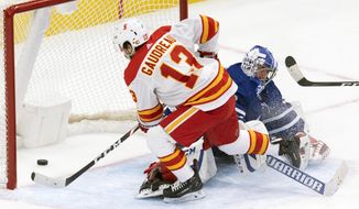 Calgary Flames&#39; Johnny Gaudreau (13) scores the game winning goal on Toronto Maple Leafs goaltender David Rittich (33) in overtime of an NHL hockey game Tuesday, April 13, 2021 in Toronto. (Frank Gunn/Canadian Press via AP)