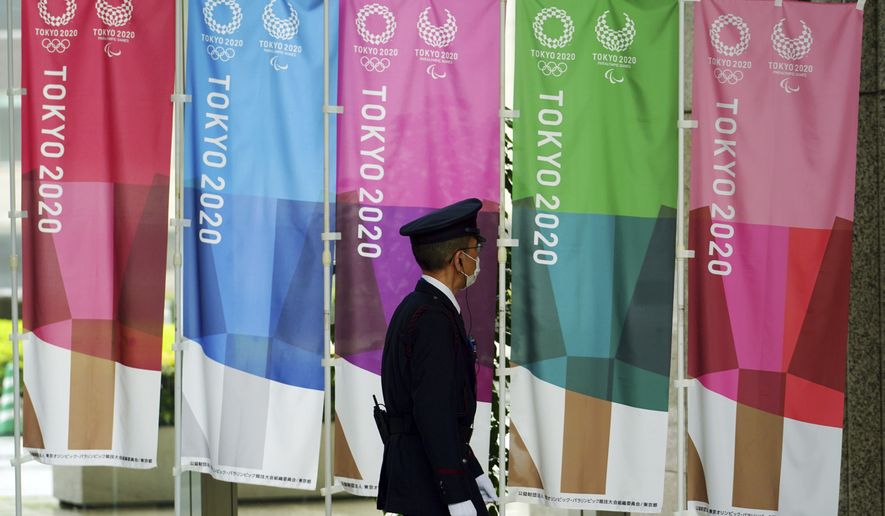 A security guard wearing a protective mask to help curb the spread of the coronavirus walks past banners for the Tokyo 2020 Olympic and Paralympic Games in Tokyo, Wednesday, April 14, 2021, to mark 100 days before the start of the Summer Games. (AP Photo/Eugene Hoshiko)