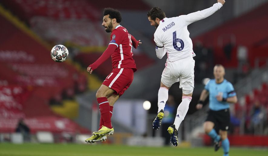 Liverpool&#x27;s Mohamed Salah, left, jumps for the ball with Real Madrid&#x27;s Nacho during a Champions League quarter final second leg soccer match between Liverpool and Real Madrid at Anfield stadium in Liverpool, England, Wednesday, April 14, 2021. (AP Photo/Jon Super)