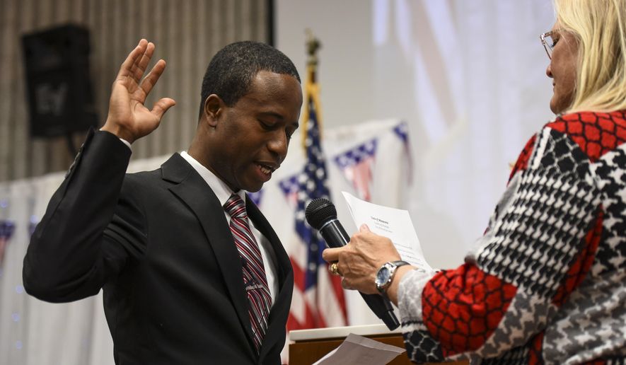 Mike Elliott takes the oath of office as the city&#x27;s new mayor with city clerk Barb Suciu, right, during Elliot&#x27;s inauguration ceremony, Wednesday, Jan. 2, 2019, at the Brooklyn Center Community Center, in Brooklyn Center, Minn. Elliott is the city&#x27;s first Black and first Liberian American mayor. Elliott, who emigrated from Liberia as a child, is finding just how difficult it is to turn the page on the nation’s racial history as he handles the fallout from a police shooting. (Aaron Lavinsky/Star Tribune via AP)