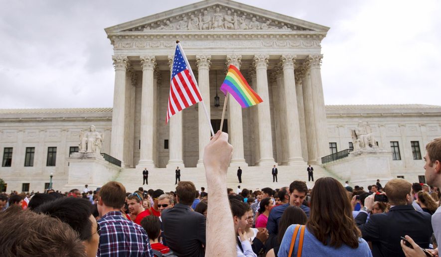 In this June 26, 2015, file photo, a man holds a U.S. and a rainbow flag outside the Supreme Court in Washington after the court legalized gay marriage nationwide. (AP Photo/Jacquelyn Martin, File)