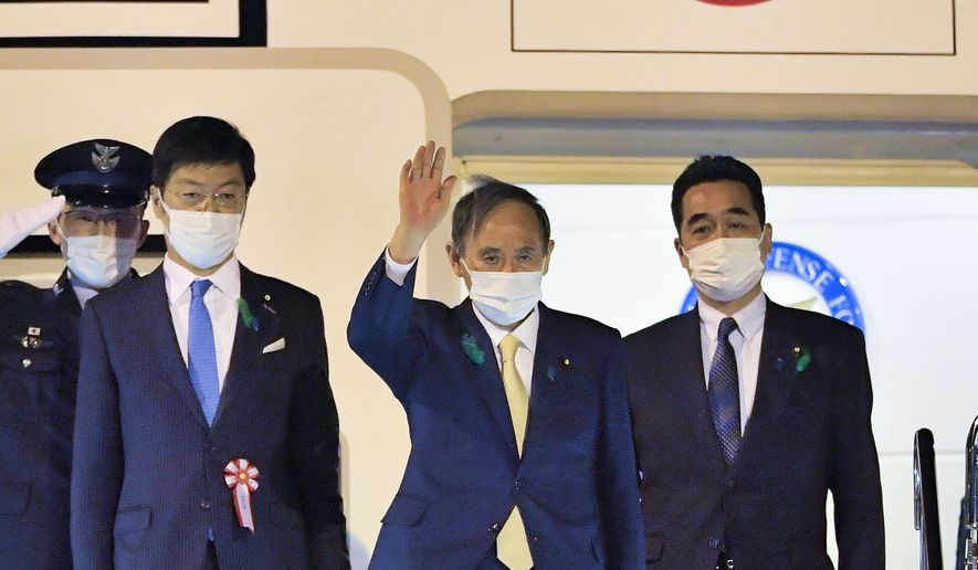 Japanese Prime Minister Yoshihide Suga, center, waves, on his departure for the U.S., at Haneda airport, in Tokyo Thursday, April 15, 2021. Suga headed to Washington on Thursday to become the first foreign leader to have a face-to-face meeting with President Joe Biden for talks that would reaffirm the strength of their alliance and how to deal with China&#39;s growing assertiveness and challenge to democratic values. (Kyodo News via AP)