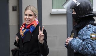 Russian opposition activist Lyubov Sobol gestures as she walks to the court escorted by a Russian Federal Bailiffs service officer in Moscow, Russia, Monday April 5, 2021.  A Moscow court will start considering the case against Navalny ally Lyubov Sobol, who is charged with unlawful entry into a dwelling. In December Sobol rang the doorbell of a flat of a relative of an alleged FSB agent Konstantin Kudryavtsev, whom Navalny accused of his poisoning. (AP Photo/Pavel Golovkin)