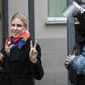 Russian opposition activist Lyubov Sobol gestures as she walks to the court escorted by a Russian Federal Bailiffs service officer in Moscow, Russia, Monday April 5, 2021.  A Moscow court will start considering the case against Navalny ally Lyubov Sobol, who is charged with unlawful entry into a dwelling. In December Sobol rang the doorbell of a flat of a relative of an alleged FSB agent Konstantin Kudryavtsev, whom Navalny accused of his poisoning. (AP Photo/Pavel Golovkin)