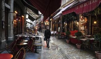 FILE - In this Oct. 2, 2020 file photo, a woman walks by empty restaurants in the center of Lyon, central France. France is expected Thursday April 15, 2021, to pass the grim milestone of 100,000 COVID-19 deaths, after a year of hospital tensions, on-and-off lockdowns and personal loss that have left families nationwide grieving the pandemic’s unending, devastating toll. (AP Photo/Laurent Cipriani, File)