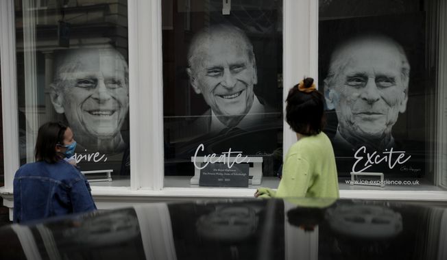 People look at images of Prince Philip displayed in the front window of &amp;quot;the Gallery at Ice&amp;quot; in Windsor, England, Wednesday, April 14, 2021. Britain&#x27;s Prince Philip, husband of Queen Elizabeth II, died Friday April 9 aged 99. His funeral service will take place on Saturday at Windsor Castle. (AP Photo/Matt Dunham)