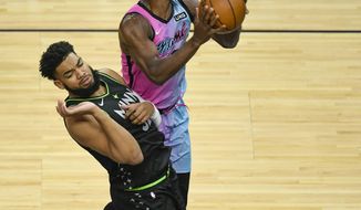 Minnesota Timberwolves center Karl-Anthony Towns, left, fouls Miami Heat forward Jimmy Butler as he goes up for a shot during the first half of an NBA basketball game Friday, April 16, 2021, in Minneapolis. (AP Photo/Craig Lassig)