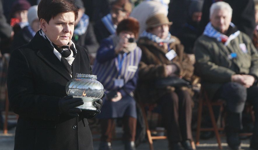 FILE - In this Friday, Jan. 27, 2017 file photo, Polish Prime Minister Beata Szydlo lights a candle at the International Monument to the Victims of Fascism, after a ceremony marking the 72nd anniversary of the liberation of the German Nazi death camp Auschwitz-Birkenau, in Oswiecim, Poland. Three of nine members appointed to an advisory council for the Auschwitz-Birkenau museum in Poland have resigned in protest after the government also named Beata Szydlo, a top right-wing ruling party member, to serve on the body it was announced Friday, April 16, 2021. The culture minister appointed Szydlo recently to a four-year term on the Auschwitz-Birkenau State Museum Council, a body made up of Poles who meet once a year to advise the director but which has little real influence. (AP Photo/Czarek Sokolowski, file)