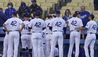 The Los Angeles Dodgers enter the dugout before their baseball game against the Colorado Rockies Thursday, April 15, 2021, in Los Angeles. All players wore jersey number 42 to honor Jackie Robinson, the first African American to play in Major League Baseball. (AP Photo/Ashley Landis) **FILE**