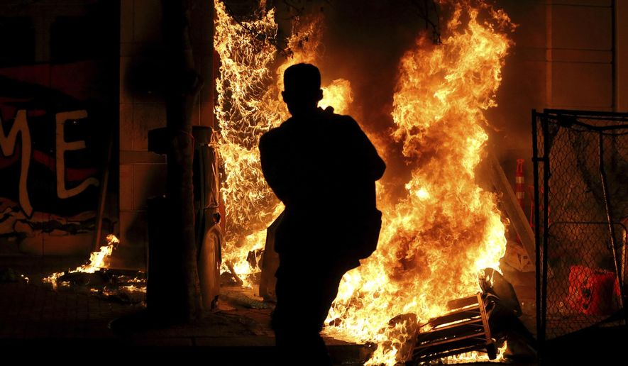 Protesters lit a portable bathroom on fire in downtown Portland, Ore., Friday, April 16, 2021. Police in Portland, Oregon, said Saturday they arrested four people after declaring a riot Friday night when protesters smashed windows, burglarized businesses and set multiple fires during demonstrations that started after police fatally shot a man while responding to reports of a person with a gun. (Dave Killen/The Oregonian via AP)