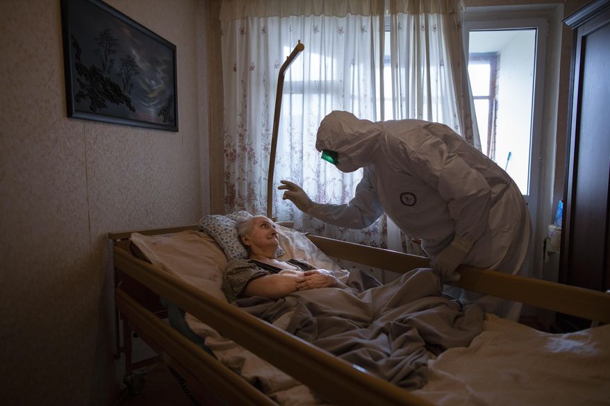 Father Vasily Gelevan, a Russian Orthodox priest, blesses Lyudmila Polyak, 86, who is believed to be suffering from COVID-19, at her apartment in Moscow, June 1, 2020. Associated Press photographer Alexander Zemlianichenko says this of the image: “I feel it’s both very intimate and also deeply symbolic, an image of empathy and self-denial in the face of mortal danger.” He says taking the photo was “also very important for me on a personal level, an experience that transformed me, helping overcome my own fear” of the virus. (AP Photo/Alexander Zemlianichenko)