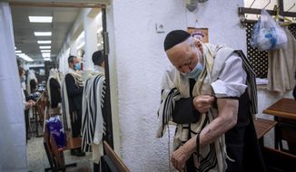 Holocaust survivor Yehoshua Datsinger places tefillin on his arm above the Auschwitz concentration camp identification number tattoo, during morning prayer at a synagogue limited to 20 people during lockdown, in Bnei Brak, Israel, Monday, Sept. 21, 2020. Photographer Oded Balilty said he was struck that even though older people were the most vulnerable to the coronavirus, Datsinger still went to synagogue every morning to pray. “He survived this latest war as well,” Balilty said. (AP Photo/Oded Balilty)