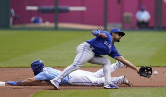 Kansas City Royals Whit Merrifield, left, steals a base behind Toronto Blue Jays second baseman Marcus Semien, right, during the first inning of a baseball game at Kauffman Stadium in Kansas City, Mo., Sunday, April 18, 2021. (AP Photo/Orlin Wagner)