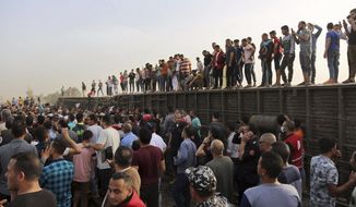 People gather at the site where a passenger train derailed injuring at least 100 people, in Banha, Qalyubia province, Egypt, Sunday, April 18, 2021. At least eight train wagons ran off the railway, the provincial governor&#x27;s office said in a statement. (AP Photo/Fadel Dawood)