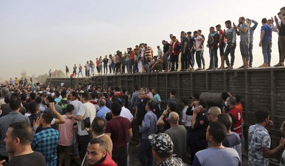 People gather at the site where a passenger train derailed injuring at least 100 people, in Banha, Qalyubia province, Egypt, Sunday, April 18, 2021. At least eight train wagons ran off the railway, the provincial governor&#39;s office said in a statement. (AP Photo/Fadel Dawood)