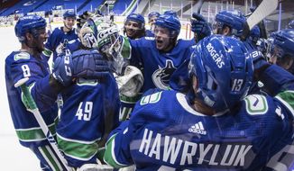 Vancouver Canucks&#39; J.T. Miller (9), goalie Braden Holtby (49) and Brock Boeser (6) celebrate with teammates after the winning goal during overtime of an NHL hockey game against the Toronto Maple Leafs in Vancouver, British Columbia, Sunday, April 18, 2021. (Darryl Dyck/The Canadian Press via AP)