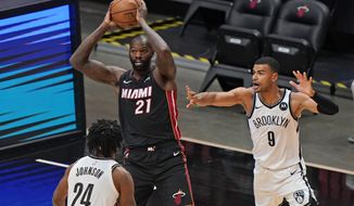 Miami Heat center Dewayne Dedmon (21) passes the ball past Brooklyn Nets forward Alize Johnson (24) and guard Timothe Luwawu-Cabarrot (9) during the first half of an NBA basketball game, Sunday, April 18, 2021, in Miami. (AP Photo/Wilfredo Lee)