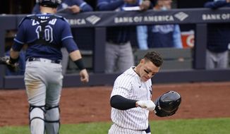 New York Yankees Aaron Judge tosses his batting helmet after striking out stranding two runners on base during the fifth inning of a baseball game against the Tampa Bay Rays, Sunday, April 18, 2021, at Yankee Stadium in New York. Rays catcher Mike Zunino (10) heads to the dugout. (AP Photo/Kathy Willens)
