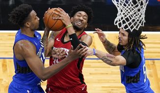 Houston Rockets center Christian Wood, center, attempts a shot against Orlando Magic center Wendell Carter Jr., left, and guard Cole Anthony, right, during the first half of an NBA basketball game, Sunday, April 18, 2021, in Orlando, Fla. (AP Photo/John Raoux)