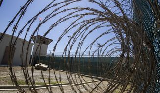 In this Wednesday, April 17, 2019, file photo reviewed by U.S. military officials, the control tower is seen through the razor wire inside the Camp VI detention facility in Guantanamo Bay Naval Base, Cuba. A plan to offer the COVID-19 vaccine to prisoners at the Guantanamo Bay detention center, which was halted earlier in 2021 amid a political backlash, is on again as health authorities on April 19, 2021, expanded the vaccination program on the Navy base in Cuba to the entire adult population of the remote facility. (AP Photo/Alex Brandon, File)