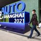 A man wearing a mask passes by a sign ahead of the Auto Shanghai 2021 show in Shanghai on Sunday, April 18, 2021. Automakers from around the world are showcasing their latest products this week in the world&#39;s biggest market for auto vehicles. (AP Photo/Ng Han Guan)