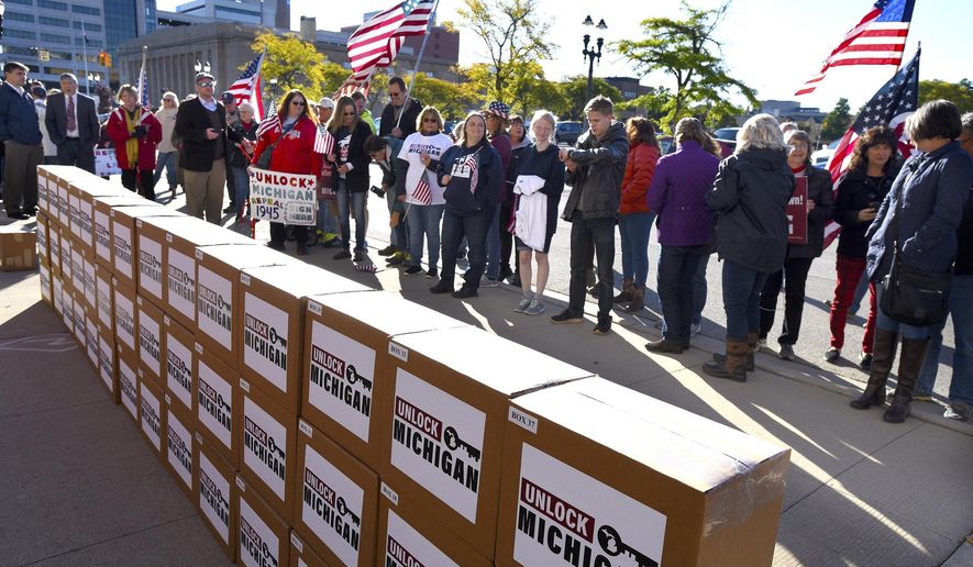 FILE - In this Oct. 2, 2020 file photo, a group gathers as boxes filled with petition signatures are delivered by Unlock Michigan to the Michigan Department of State Bureau of Elections in Lansing, Mich. A group trying to repeal an emergency powers law that Gov. Gretchen Whitmer used for months to issue coronavirus restrictions cleared a key hurdle Monday, April 19, 2021 when the Michigan elections bureau said it collected enough petitions. (Rod Sanford/Detroit News via AP)