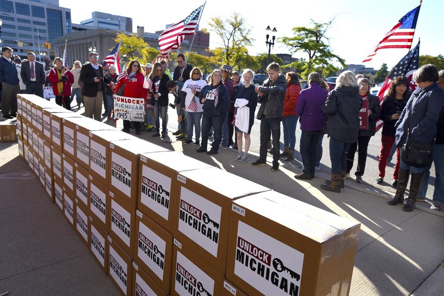 FILE - In this Oct. 2, 2020 file photo, a group gathers as boxes filled with petition signatures are delivered by Unlock Michigan to the Michigan Department of State Bureau of Elections in Lansing, Mich. A group trying to repeal an emergency powers law that Gov. Gretchen Whitmer used for months to issue coronavirus restrictions cleared a key hurdle Monday, April 19, 2021 when the Michigan elections bureau said it collected enough petitions. (Rod Sanford/Detroit News via AP)