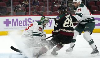 Minnesota Wild goaltender Cam Talbot (33) makes a save on a shot from Arizona Coyotes left wing Dryden Hunt (28) as Wild defenseman Carson Soucy (21) applies pressure during the first period of an NHL hockey game Monday, April 19, 2021, in Glendale, Ariz. (AP Photo/Ross D. Franklin)
