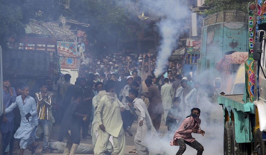 Supporters of Tehreek-e-Labiak Pakistan, a banned Islamist party, react after police fire tear gas to disperse them while protesting the arrest of their party leader Saad Rizvi, in Karachi, Pakistan, Monday, April 19, 2021. The outlawed Islamist political group freed 11 policemen almost a day after taking them hostage in the eastern city of Lahore amid violent clashes with security forces, the country's interior minister said Monday. (AP Photo/Fareed Khan)