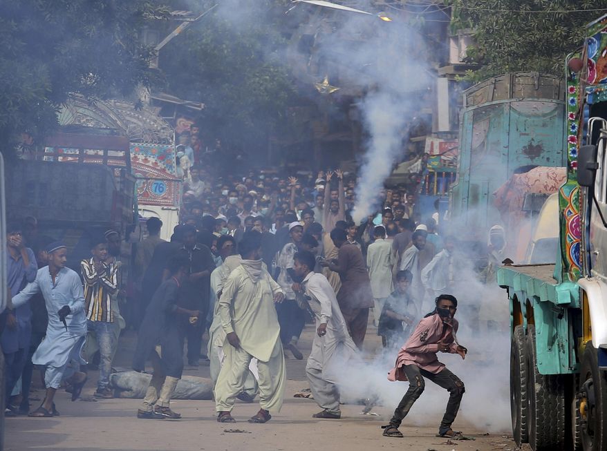 Supporters of Tehreek-e-Labiak Pakistan, a banned Islamist party, react after police fire tear gas to disperse them while protesting the arrest of their party leader Saad Rizvi, in Karachi, Pakistan, Monday, April 19, 2021. The outlawed Islamist political group freed 11 policemen almost a day after taking them hostage in the eastern city of Lahore amid violent clashes with security forces, the country's interior minister said Monday. (AP Photo/Fareed Khan)
