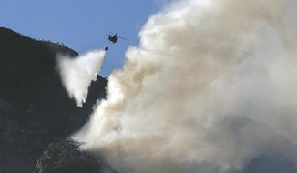 A South African military helicopter drops water on the top of Table Mountain in Cape Town, South Africa, Tuesday, April 20, 2021. A massive fire spreading on the slopes of the city&#39;s famed Table Mountain is kept under control as firemen and helicopters take advantage of the low winds to contain the blaze. (AP Photo/Jerome Delay)